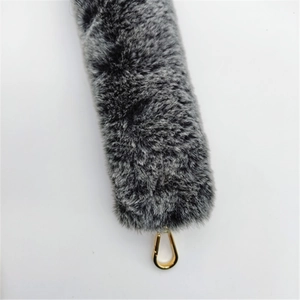 Detail of grey-black faux fur bag strap featuring a glossy golden metal spring clasp