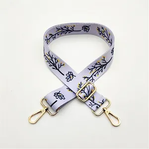 Détail de la bandoulière réglable en toile lavande à motifs floraux avec crochets dorés
