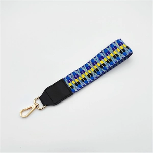 Detailed view of geometric woven strap with black leather trim and gold swivel hook
