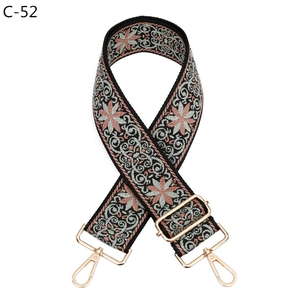 Detail view of the floral patterned woven bag strap with gold metal buckles and hooks