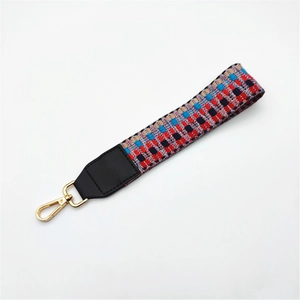 Detailed macro view of woven checkered purse strap with gold lobster clasp and leather trim
