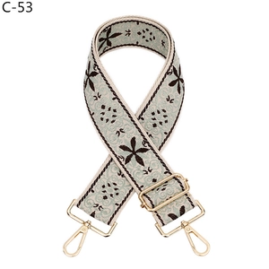 Detail view of woven floral bag strap with mint green patterns and gold metal hooks