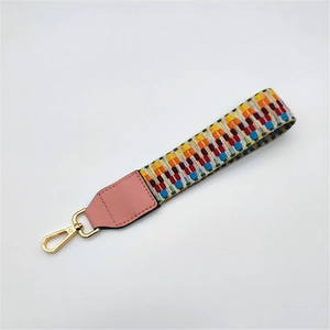 Detail of colorful woven wrist strap with geometric patterns and gold metal clasp