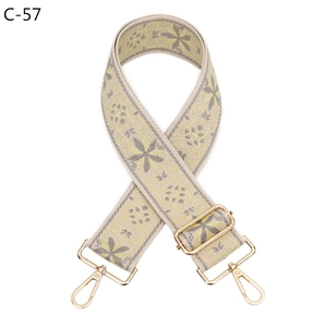 Close-up of adjustable jacquard bag strap with grey and yellow floral pattern and gold clasps