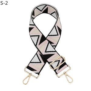 Detail of adjustable woven wide strap with geometric chevron pattern and gold metal hooks
