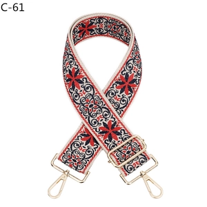 Detail of adjustable woven shoulder strap with red ethnic floral pattern and gold hooks