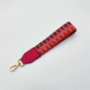 Close-up of multicolor woven wrist strap with pink leather trim and gold lobster clasp