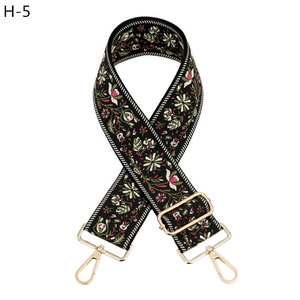 Close-up of wide woven bag strap with colorful floral embroidery and gold metal hardware