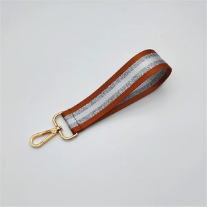 Detail of orange and silver striped wristlet strap with a polished golden lobster clasp