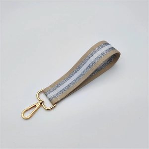 Detail showing beige fabric wrist strap with silver glitter stripes and gold metal clasp