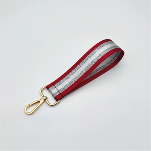 Detail of red and gray striped braided wrist strap with a shiny gold lobster clasp