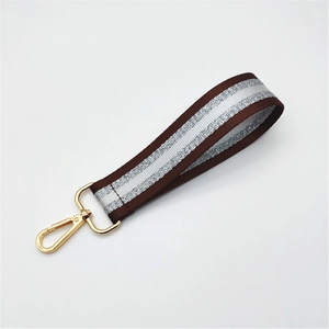 Detail of coffee woven wrist strap with silver glitter and gold lobster clasp