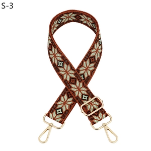 Detail of floral woven bag strap with golden metal hooks and adjustable buckle