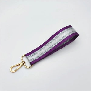 Detail of purple and silver striped nylon strap with a gold lobster clasp for bags