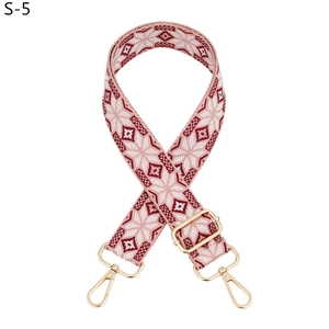 Detail of adjustable woven shoulder strap with pink snowflake pattern and gold metal hooks