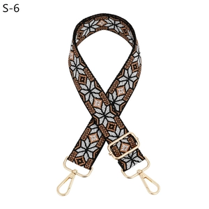 Close-up of ethnic geometric jacquard woven bag strap with golden lobster clasps and buckles