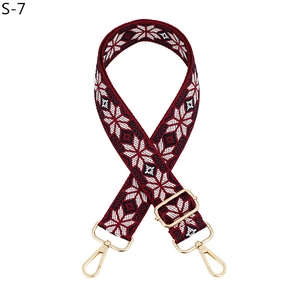 Detail of burgundy woven strap with white snowflake patterns and gold metal hooks
