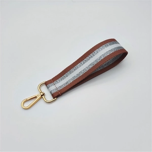 Close-up of brown and silver glitter strap with a golden metallic spring hook clasp