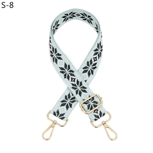 Detail of adjustable blue fabric strap with black snowflake pattern and gold metal hooks