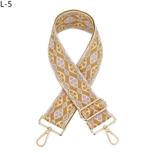 Detail von geometrischem Jacquard-Taschenriemen mit goldenen Karabinern und Schnalle
