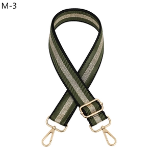 Detail of adjustable bag strap with green, gold and black metallic stripes and gold buckle