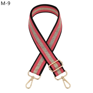 Close-up of adjustable woven bag strap with pink stripes and gold metal hardware