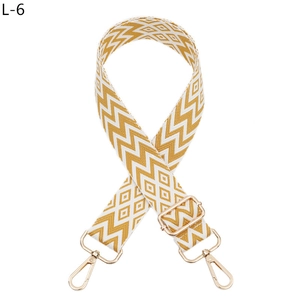 Detail of adjustable woven bag strap with yellow geometric patterns and gold metal clips