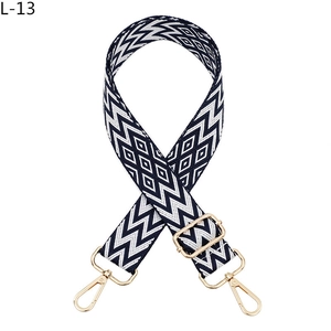 Close-up of geometric jacquard bag strap with gold metal swivel snap hooks and buckle