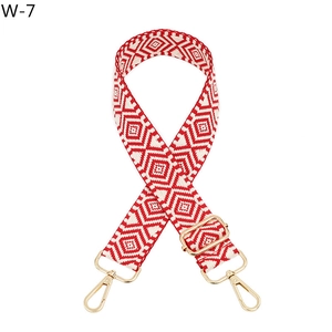 Detail of red and white geometric ethnic pattern bag strap with gold metal hardware