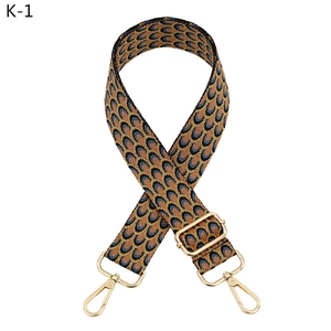 Detail of adjustable peacock pattern woven bag strap with golden lobster metal clasps