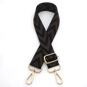 Detail view of woven brown and black herringbone bag strap with gold metal buckles