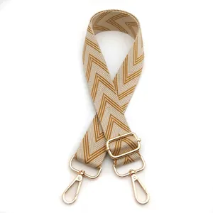 Close-up of adjustable woven shoulder strap with mustard yellow herringbone pattern and gold hooks