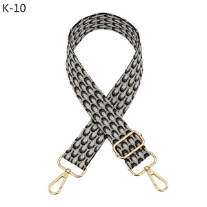 Detail of adjustable geometric patterned bag strap with golden metal lobster clasps