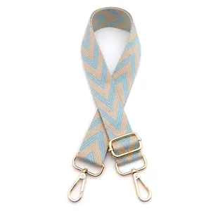 Detail view of adjustable woven bag strap with blue chevron pattern and gold metal hooks
