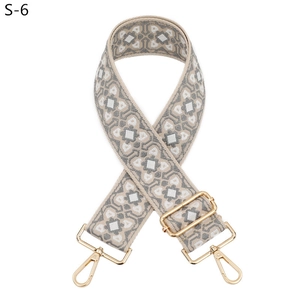Dettaglio della tracolla larga regolabile in jacquard con motivi geometrici e clip oro