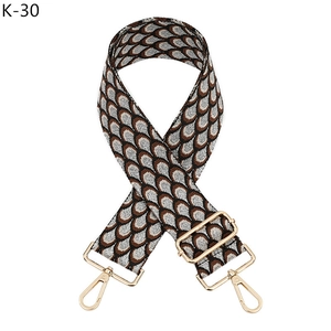 Dettaglio della tracolla jacquard con ganci dorati e motivi geometrici a squame