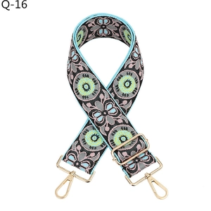 Close-up of jacquard embroidered bag strap with floral patterns and gold metal hooks