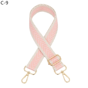 Detailed view of pink and beige woven chevron guitar strap with gold metal buckles