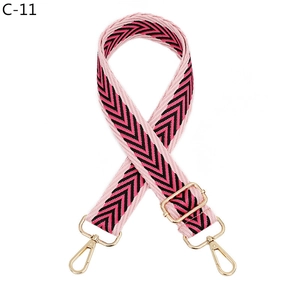 Detail of adjustable woven jacquard bag strap with pink V-pattern and gold hooks