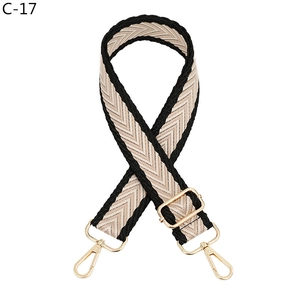Detail of adjustable woven jacquard strap with gold-tone swivel hooks and slider buckle