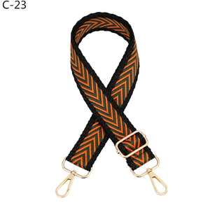 Detail of adjustable woven handbag strap with orange and green chevron pattern and gold clips