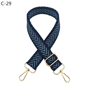 Detail of navy blue herringbone patterned wide bag strap with gold metal swiveling hardware