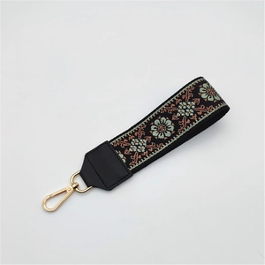 Close-up of ethnic embroidered bag strap with floral pattern and gold metal lobster clasp