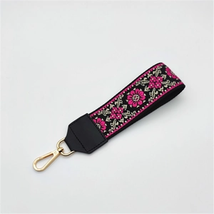Detailed view of ethnic embroidery handbag wrist strap with floral patterns and gold clasp