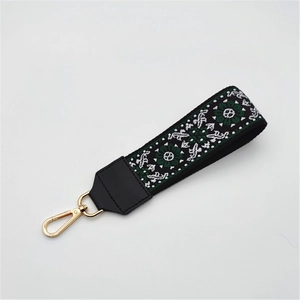 Detail view of ethnic jacquard woven strap with floral pattern and golden metal clasp hook