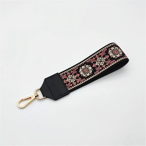 Detailed macro of ethnic floral embroidery on black strap with gold swivel hook