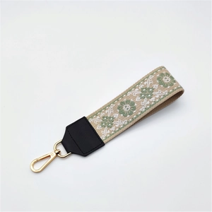 Close-up of ethnic style embroidered strap with green floral patterns and gold lobster clasp