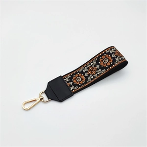Detail of bohemian floral embroidery bag strap with gold metal lobster clasp and leather end