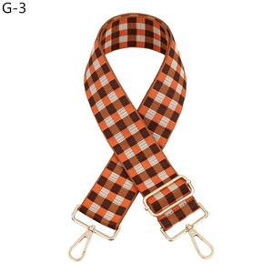 Close-up of woven checkered purse strap in orange and brown with gold metal clips