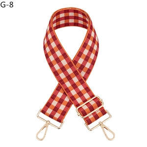 Detail view of red and orange checkered bag strap with adjustable gold hardware